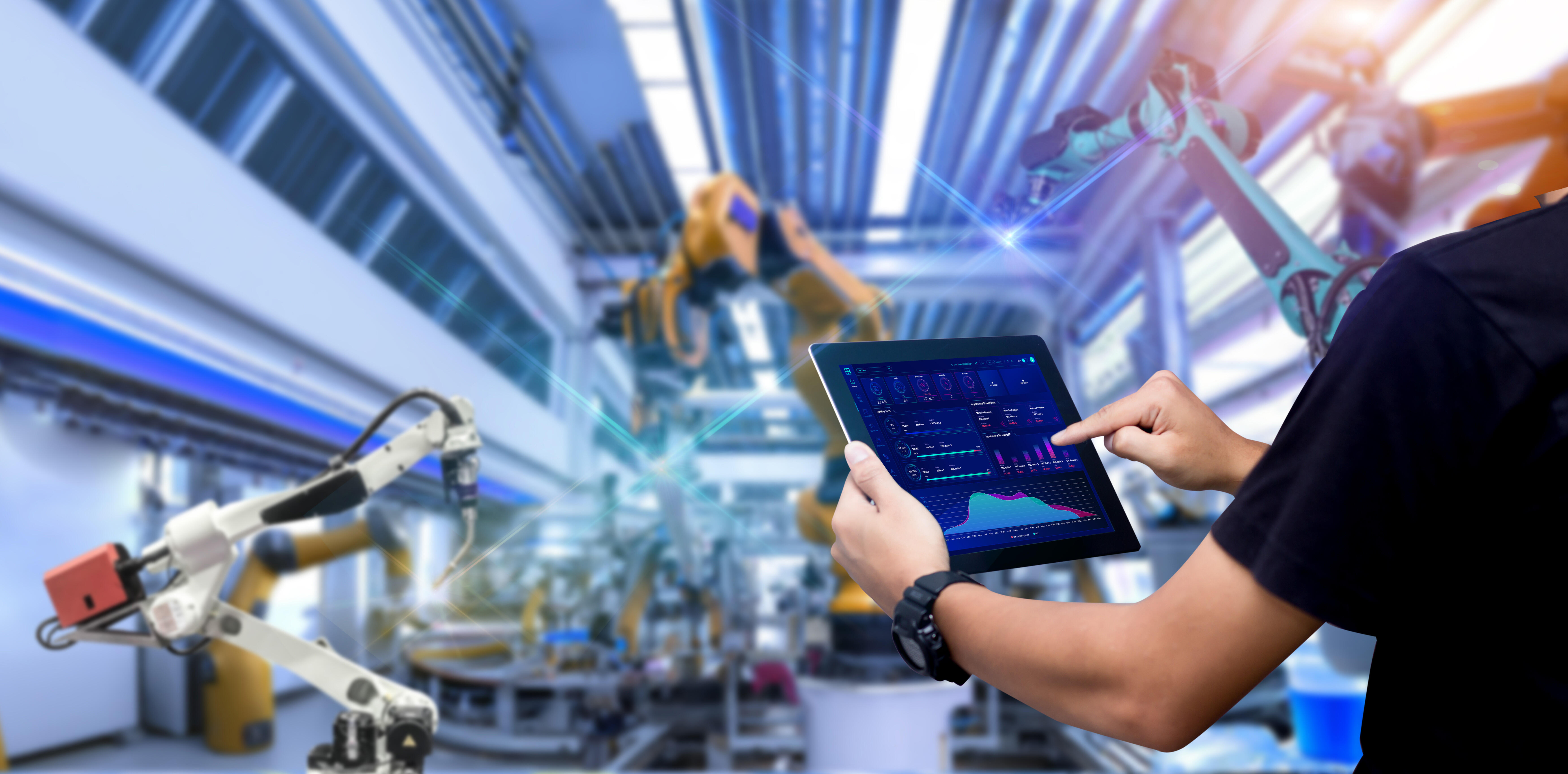 Clouver Dashboard auf Tablet vor einer Halle mit Maschinen